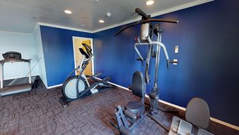 Secondary view of the fitness center with strength training and cardio machines with ample floor space for exercise.